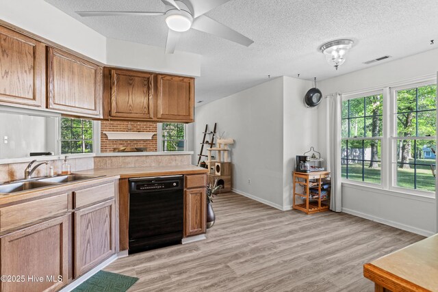 kitchen with a textured ceiling, light wood-style flooring, a sink, visible vents, and dishwasher