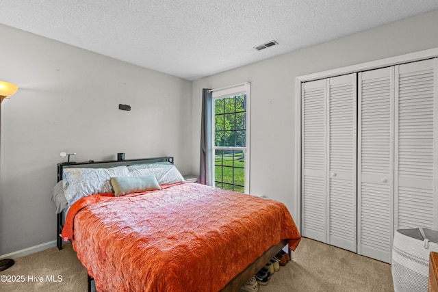 bedroom featuring a closet, visible vents, carpet, baseboards, and a textured ceiling