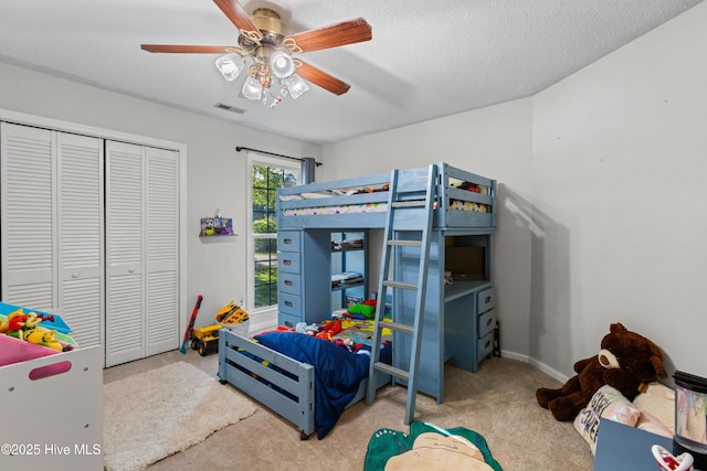 carpeted bedroom featuring a closet, a ceiling fan, visible vents, baseboards, and a textured ceiling