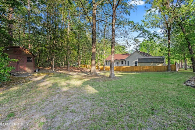 view of yard with an outdoor structure, a storage unit, and fence