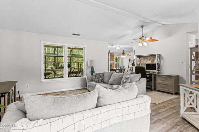 living room featuring visible vents, wood finished floors, a ceiling fan, and lofted ceiling with beams