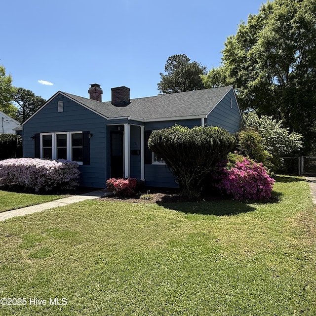 single story home with a chimney, a front lawn, and roof with shingles