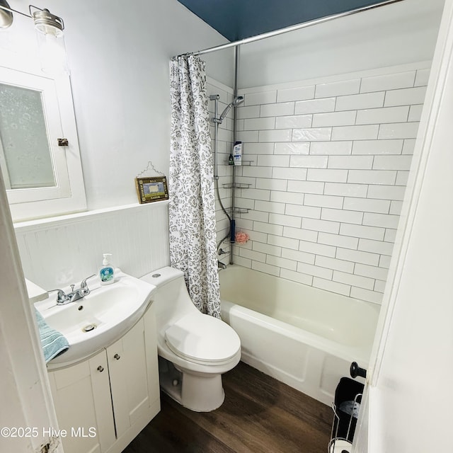 full bathroom with wood finished floors, wainscoting, vanity, shower / tub combo with curtain, and toilet