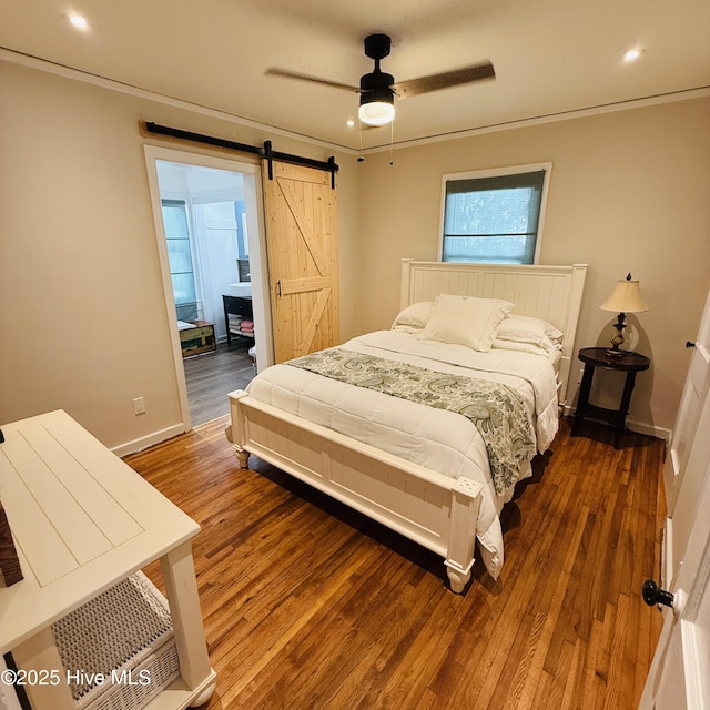 bedroom with baseboards, wood finished floors, recessed lighting, and a barn door