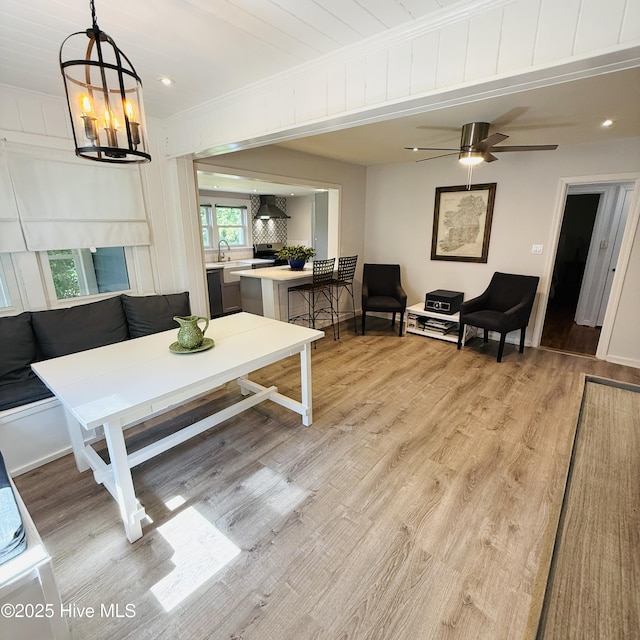 living room featuring ornamental molding, baseboards, a ceiling fan, and light wood-style floors