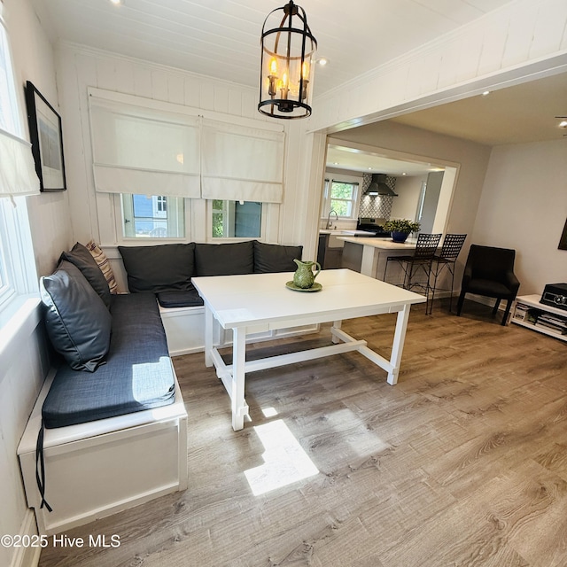 living area featuring light wood finished floors, breakfast area, crown molding, and a healthy amount of sunlight