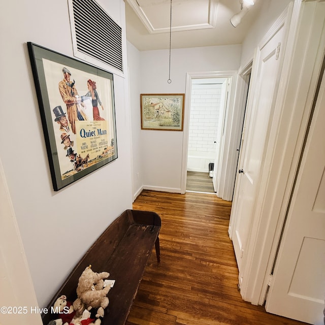 hall with attic access, wood finished floors, visible vents, and baseboards