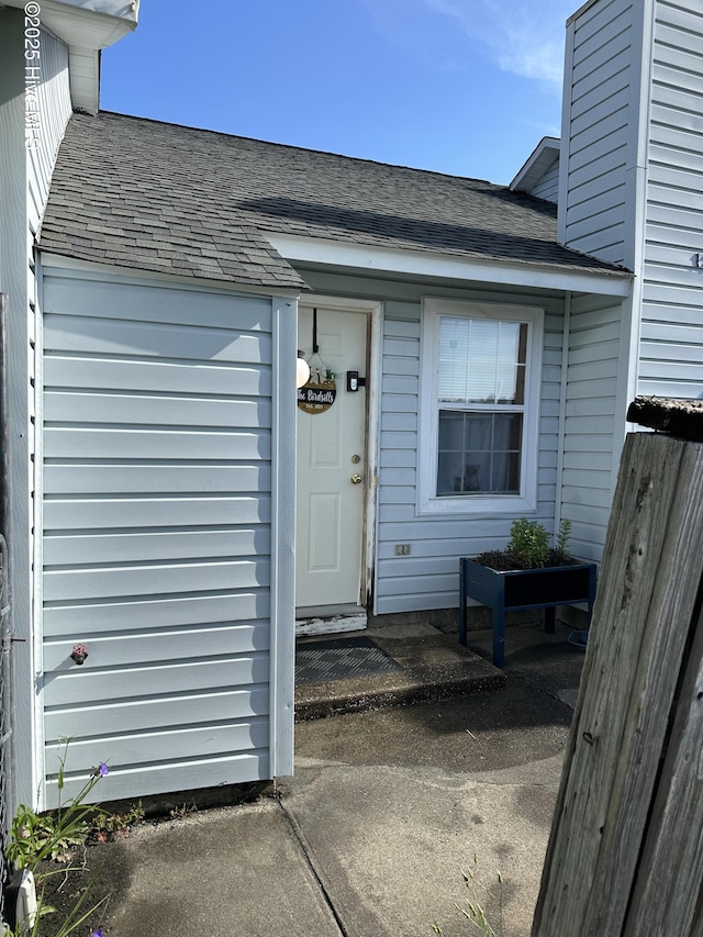 view of exterior entry with a shingled roof