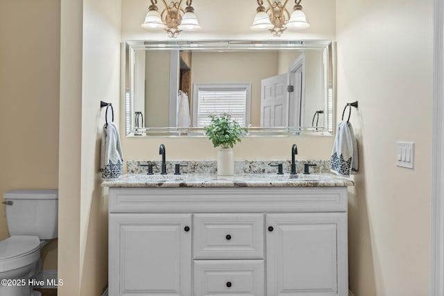 full bath with toilet, double vanity, and a sink