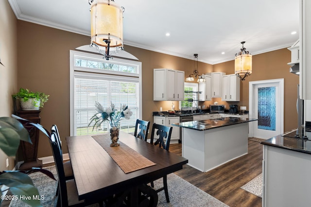 kitchen featuring white cabinetry, dark countertops, a center island, ornamental molding, and dark wood-type flooring
