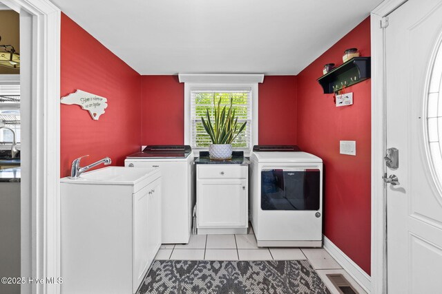 laundry area featuring independent washer and dryer, light tile patterned floors, cabinet space, a sink, and visible vents