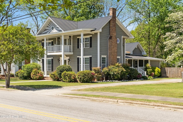 greek revival house featuring a chimney, fence, a porch, and a front yard