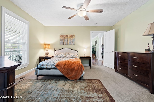 bedroom with light colored carpet, visible vents, a textured ceiling, and baseboards