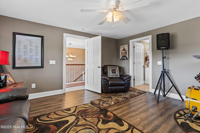 living room with baseboards, wood finished floors, and ceiling fan with notable chandelier