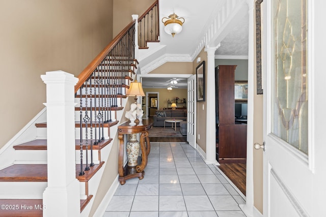 entryway featuring stairs, decorative columns, marble finish floor, ceiling fan, and crown molding