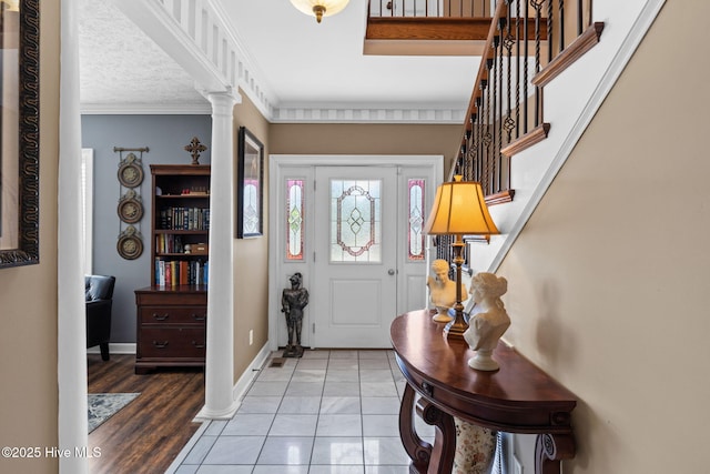 entrance foyer with crown molding, stairs, baseboards, and ornate columns