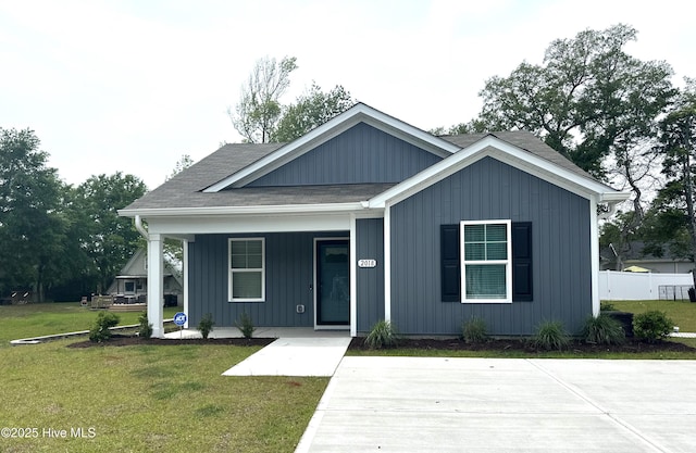 view of front of house featuring a porch, a front lawn, and roof with shingles