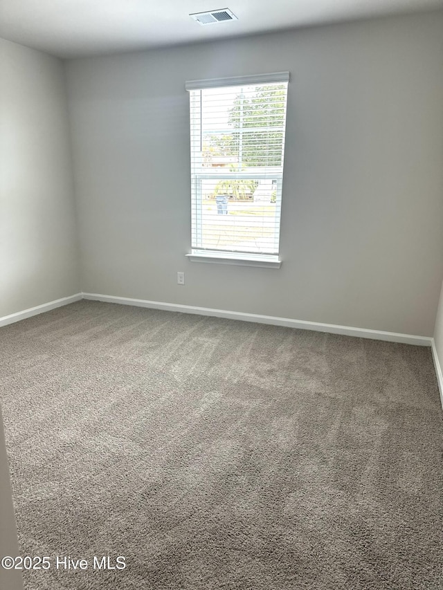 carpeted spare room featuring visible vents and baseboards