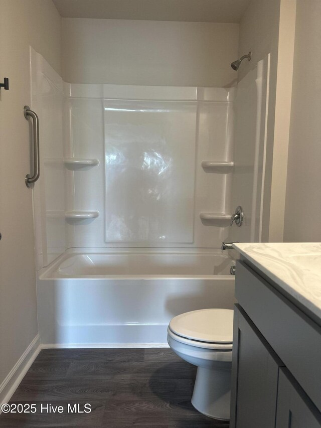 bathroom with tub / shower combination, baseboards, toilet, wood finished floors, and vanity