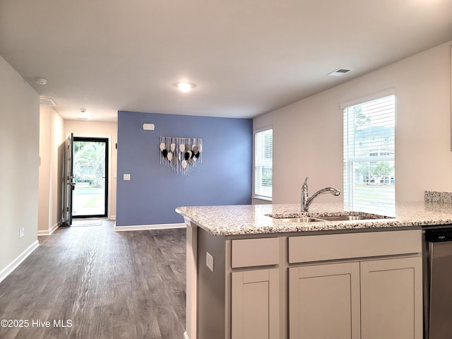 kitchen with dishwasher, a sink, light stone countertops, and dark wood finished floors