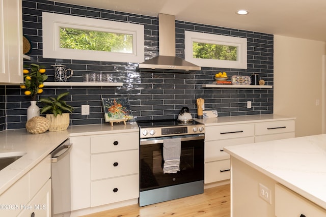 kitchen with stainless steel appliances, open shelves, wall chimney exhaust hood, and plenty of natural light