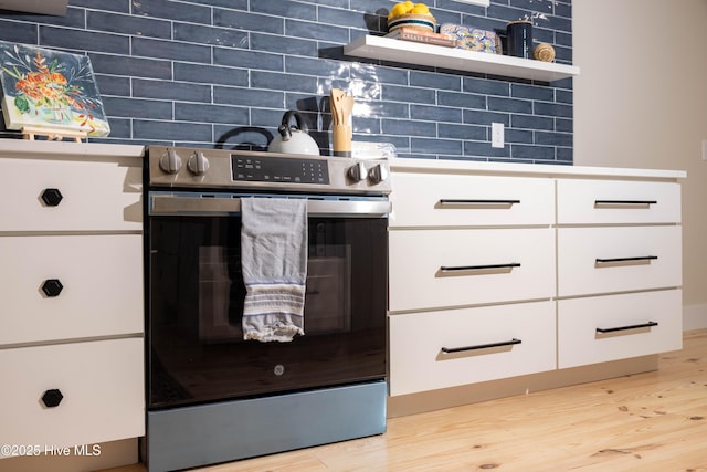 interior details featuring light wood finished floors, open shelves, stainless steel electric range oven, backsplash, and white cabinets