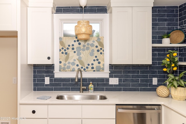 kitchen with a sink, decorative backsplash, white cabinetry, light countertops, and stainless steel dishwasher