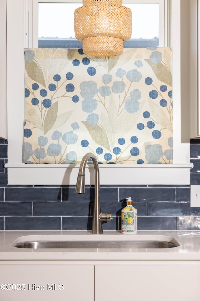 interior details with white cabinetry, backsplash, and a sink