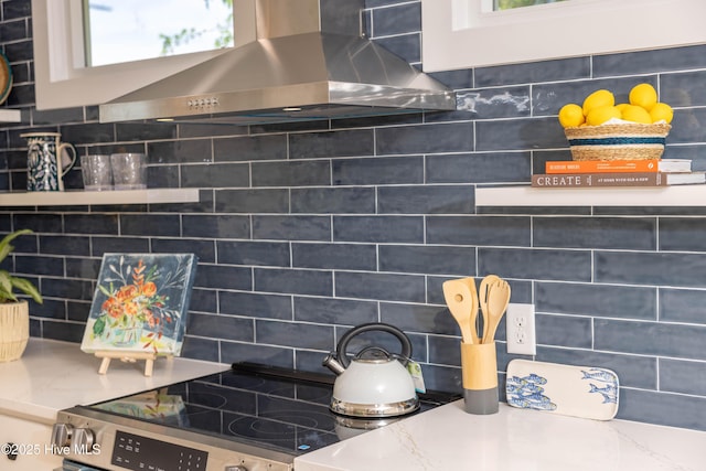 room details featuring electric stove, backsplash, and wall chimney range hood