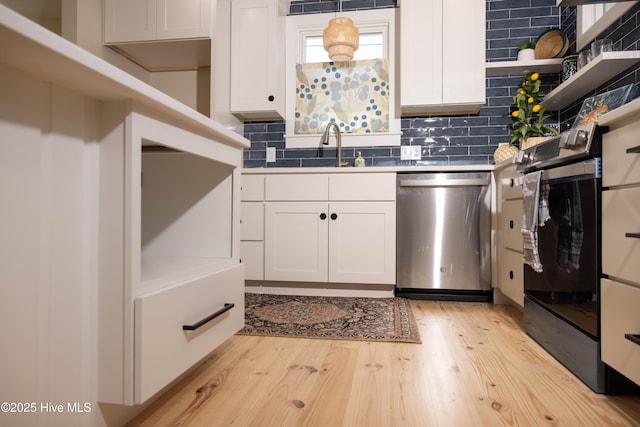 kitchen with white cabinetry, light wood-type flooring, stainless steel dishwasher, and a sink