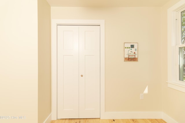 unfurnished bedroom featuring light wood-style floors, a closet, and baseboards