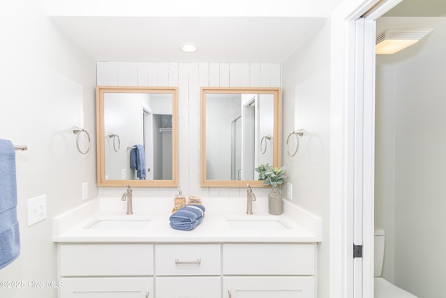 bathroom with toilet, recessed lighting, double vanity, and a sink