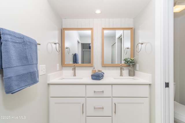 bathroom featuring toilet, recessed lighting, double vanity, and a sink
