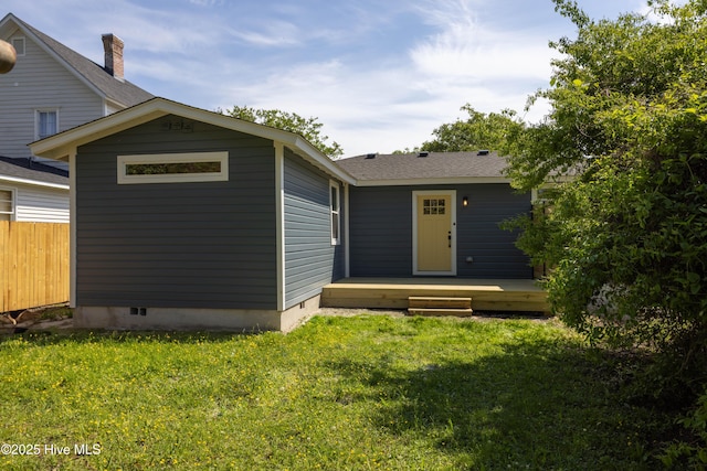 rear view of house with a lawn, fence, and a wooden deck