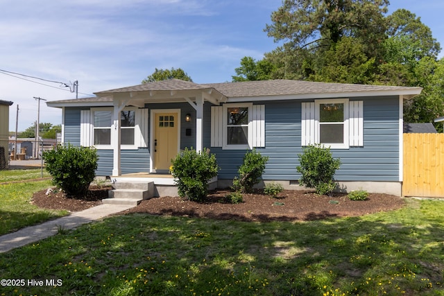 view of front of home featuring fence, roof with shingles, and a front lawn