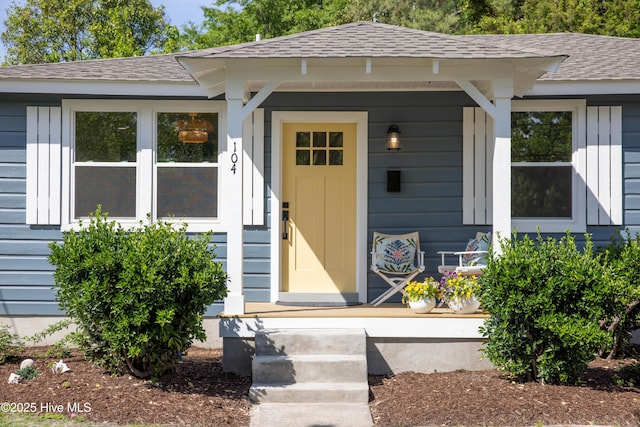 doorway to property with a shingled roof and covered porch