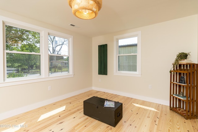 spare room with baseboards, visible vents, and wood finished floors