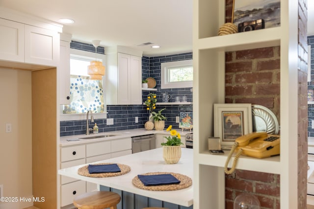 kitchen featuring open shelves, light countertops, a kitchen bar, a sink, and white cabinetry