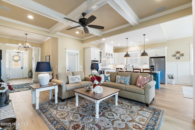 living area with beam ceiling, a ceiling fan, light wood finished floors, ornamental molding, and a chandelier