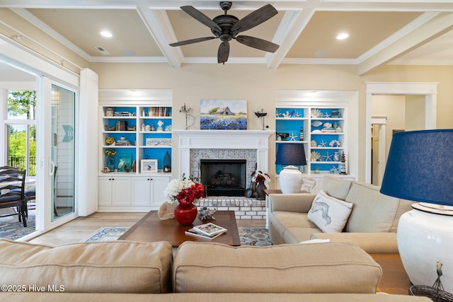 living room with ornamental molding, wood finished floors, beamed ceiling, a fireplace, and ceiling fan