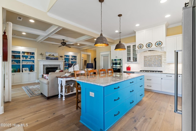 kitchen with gas cooktop, a kitchen breakfast bar, a ceiling fan, coffered ceiling, and white cabinetry