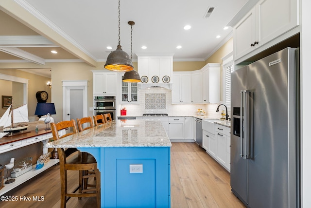 kitchen featuring appliances with stainless steel finishes, a breakfast bar area, a sink, crown molding, and white cabinets