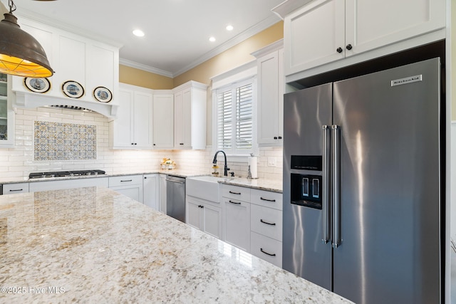 kitchen featuring stainless steel appliances, a sink, ornamental molding, white cabinets, and decorative backsplash