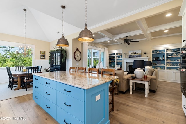 kitchen with blue cabinets, a breakfast bar area, ceiling fan, light wood-type flooring, and a chandelier