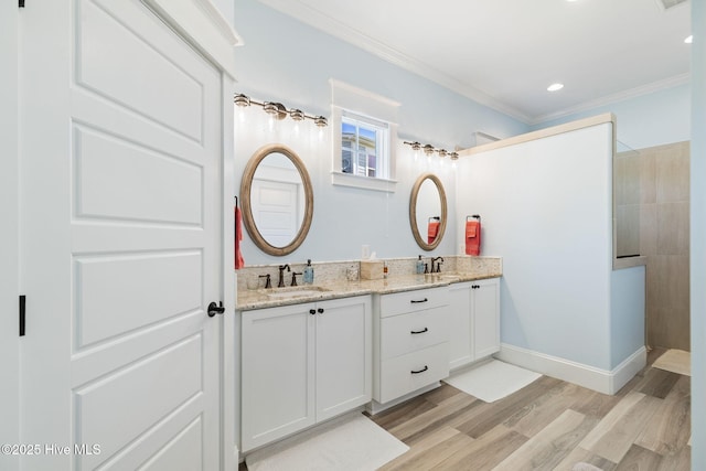 full bath featuring double vanity, wood finished floors, walk in shower, crown molding, and baseboards
