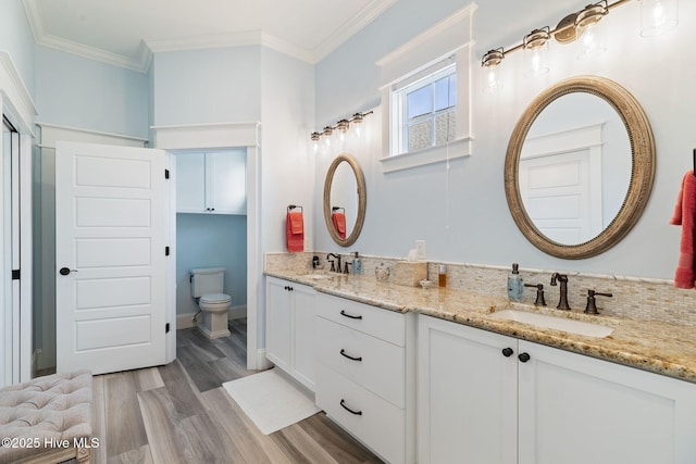 full bath featuring wood finished floors, toilet, double vanity, and ornamental molding