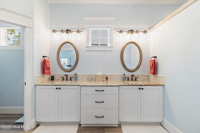 full bath with double vanity, wood finished floors, and baseboards