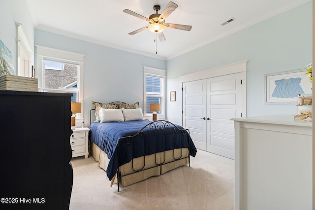 bedroom with light carpet, ornamental molding, a closet, and a ceiling fan
