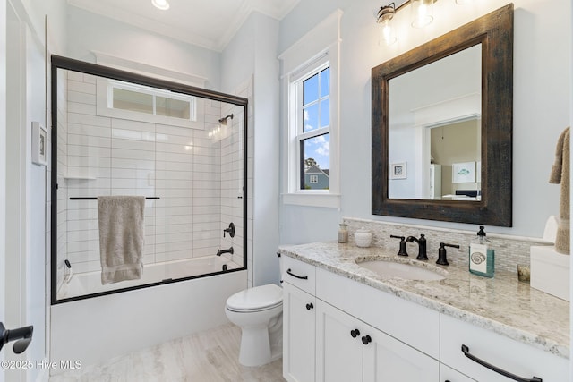 full bath featuring crown molding, backsplash, vanity, toilet, and shower / bath combination with glass door