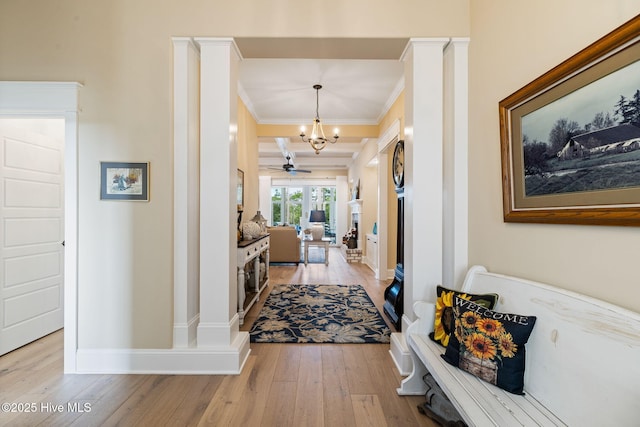hall featuring ornamental molding, light wood-style flooring, a chandelier, and baseboards